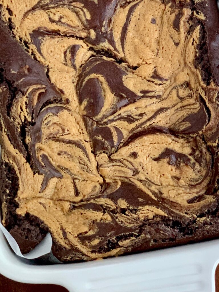 A peanut butter mixture swirled in brownie batter in a baking pan. 