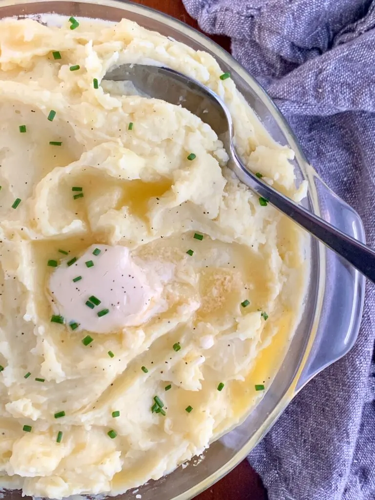 creamy mashed potatoes with melted dairy free butter on top with chopped herbs