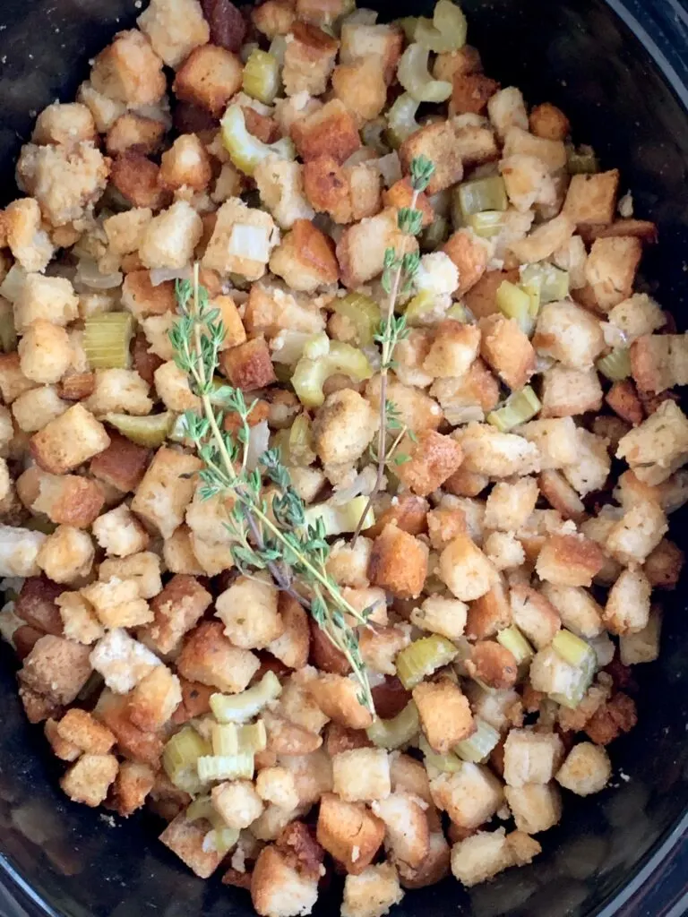 A crock-pot full of stuffing such as cubed bread, and chopped onions and celery.