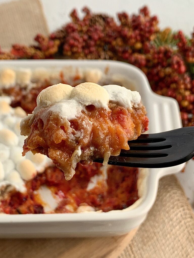 a forkful of baked sweet potato bake next to a baking pan of more mixture.