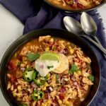 Taco soup in 2 bowls topped with dairy free sour cream, green onions, and cilantro.