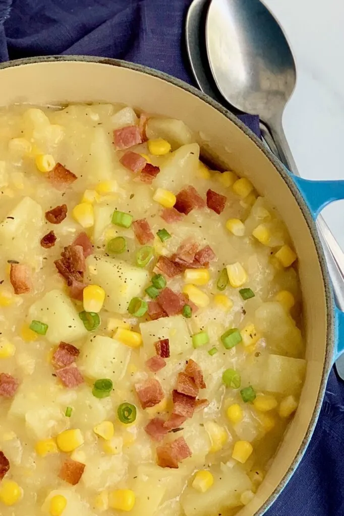 A bowl full of creamy potato corn chowder topped with bacon and green onions.