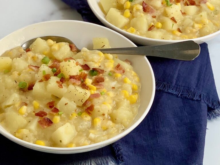 A bowl full of creamy potato corn chowder topped with bacon and green onions.