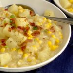 A bowl of creamy potato chowder with corn, bacon, and green onions.