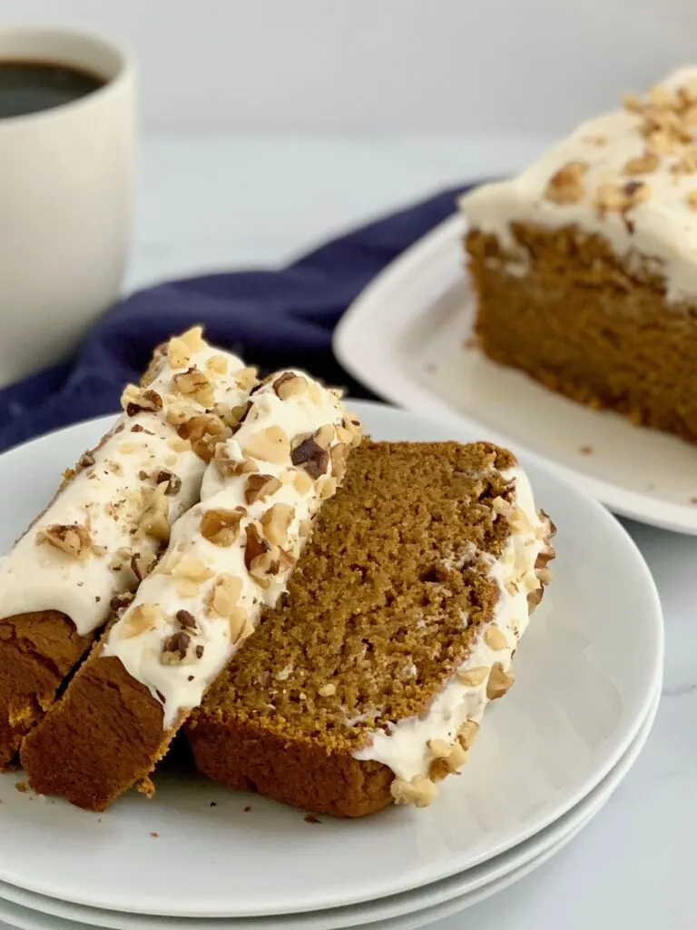 3 slices of pumpkin bread with cream cheese frosting and walnuts on a plate