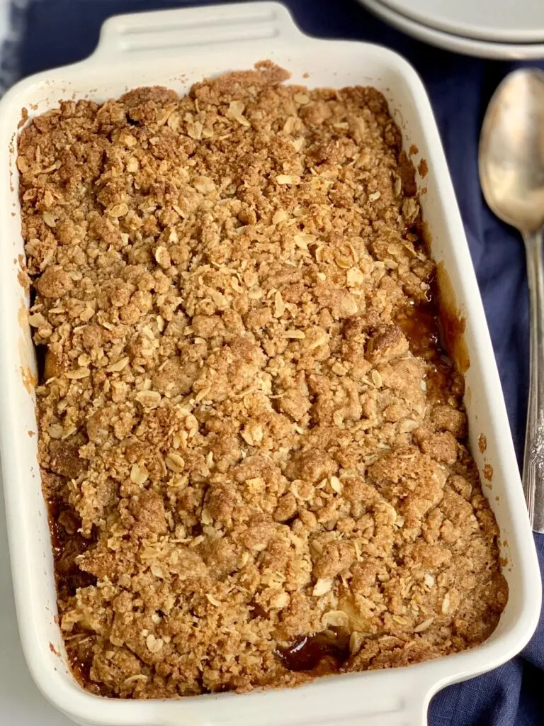 A baked pan of apples topped with a brown sugar, oatmeal, and butter topping.