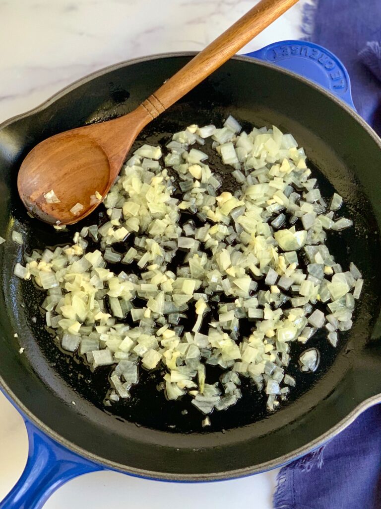 A skillet with diced onions and minced garlic.