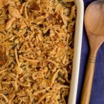 A baking dish with creamy mushroom soup. green beans, and crispy French fried onions on top.