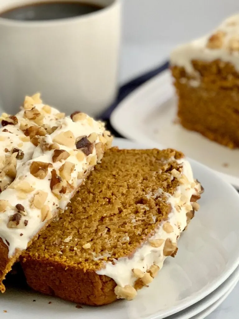 Sliced layers of pumpkin bread iced with a dairy free cream cheese frosting.