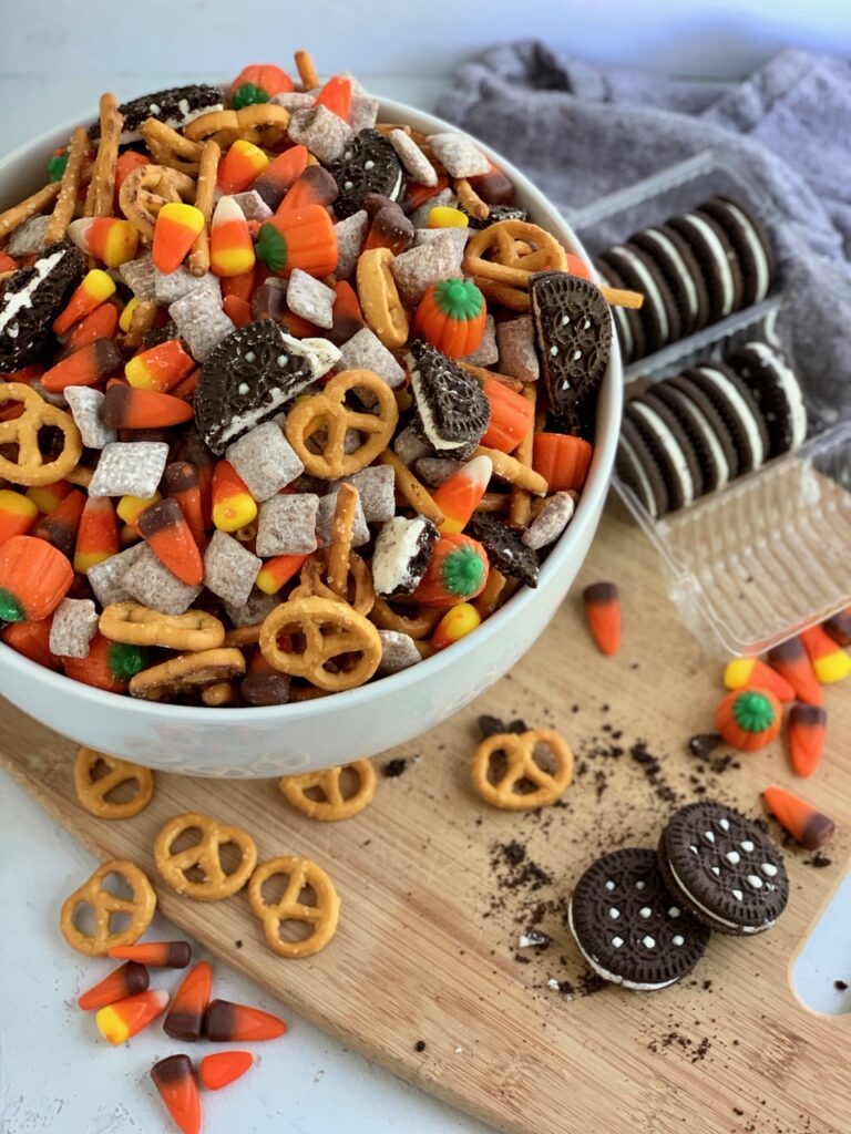 a bit party bowl of pretzels, puppy chow, candy corns, and oreo like sandwich cookies