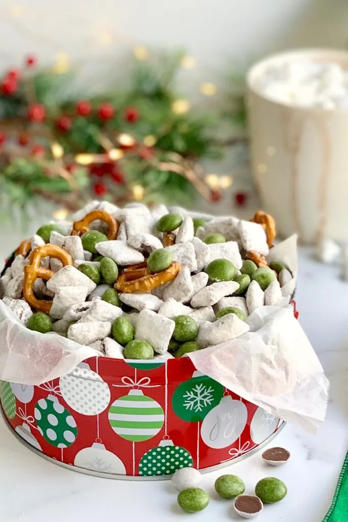 A holiday tin filled with homemade puppy chow, pretzels twists, and No Whey Peppermint No No's