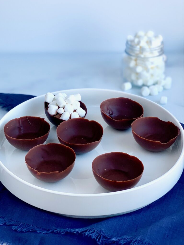 A platter full of 6 empty chocolate wells.