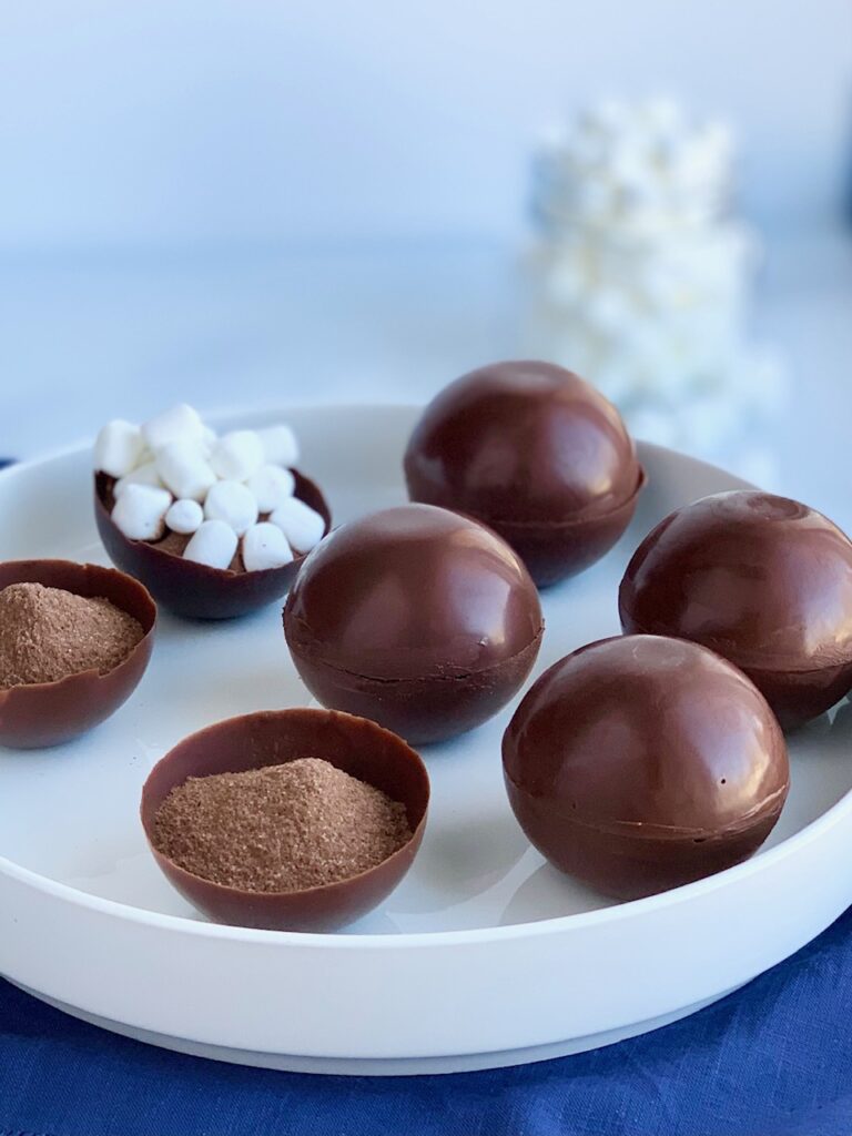A platter full of thin chocolate balls stuffed with hot chocolate mix and mini marshmallows.