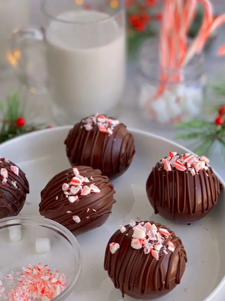 5 hollow chocolate balls filled with hot cocoa mix and topped with melted chocolate drizzle and crushed candy canes.