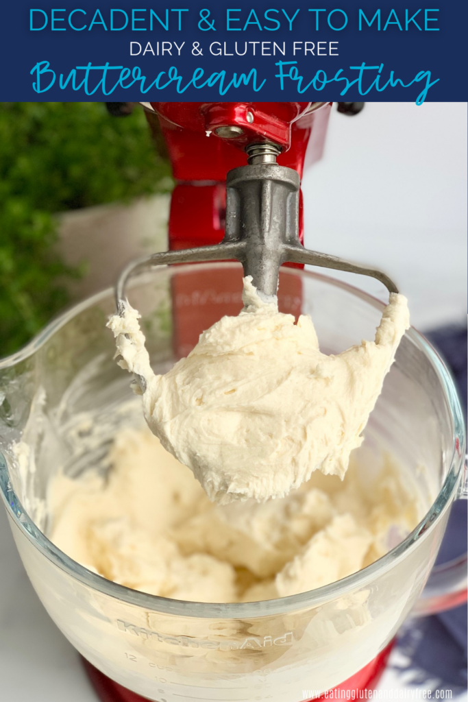 A kitchen mixer with the paddle attachment on it and buttercream frosting all over it.