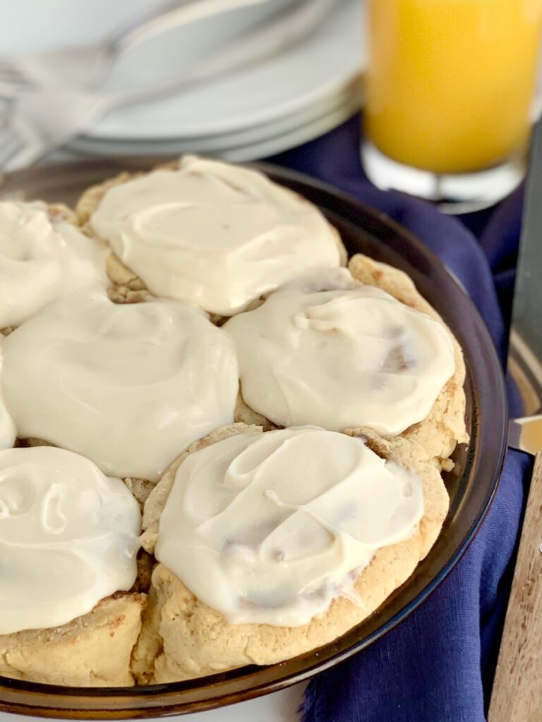 A pie plate full of 7 cinnamon rolls with a creamy cream cheese frosting.