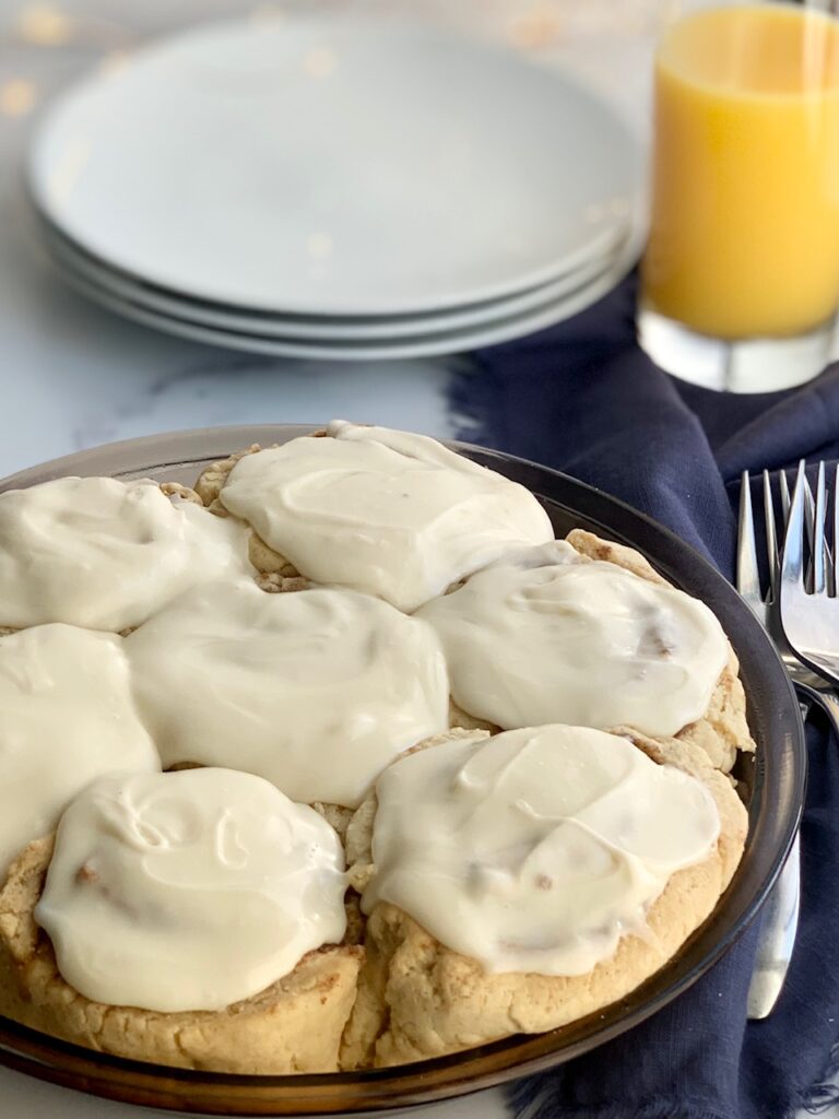 A pie plate full of 7 cinnamon rolls with a creamy cream cheese frosting.