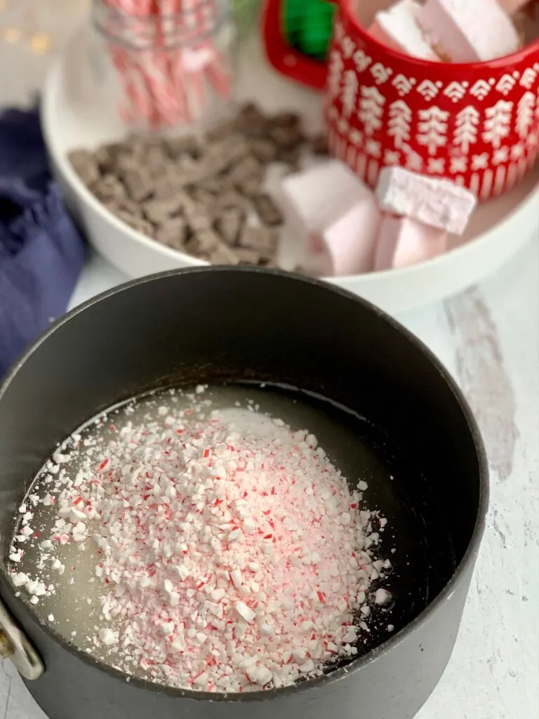 A mixture of granulated sugar, corn syrup, and crushed candy canes in a saucepan.