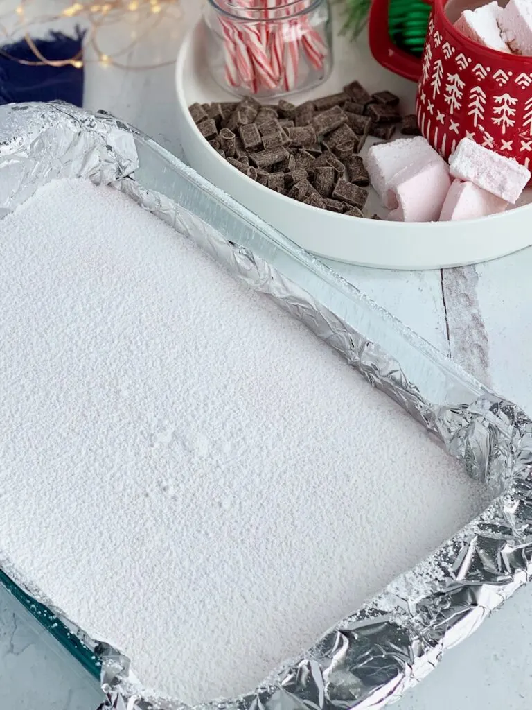 The 9 x 13 inch baking pan full of the marshmallow mixture topped with a dusting of cornstarch and powdered sugar before being cut.