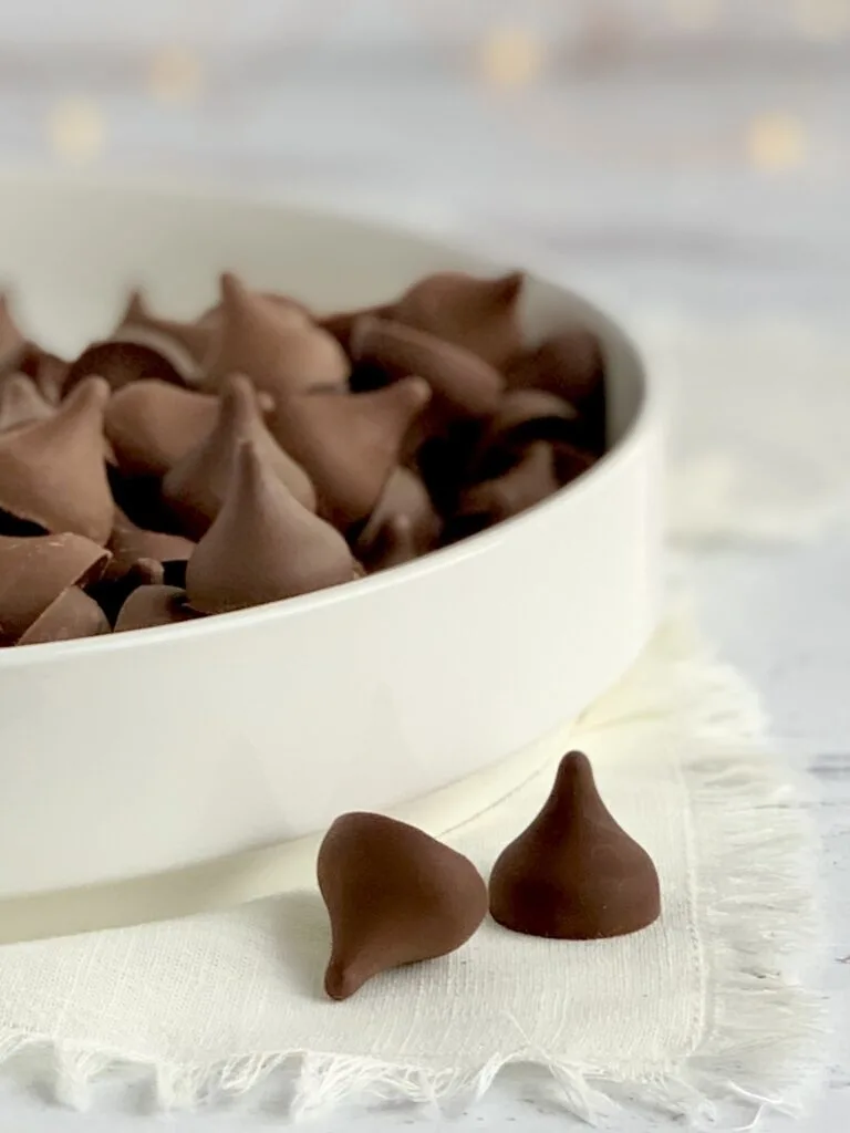 A white platter full of chocolate kisses.