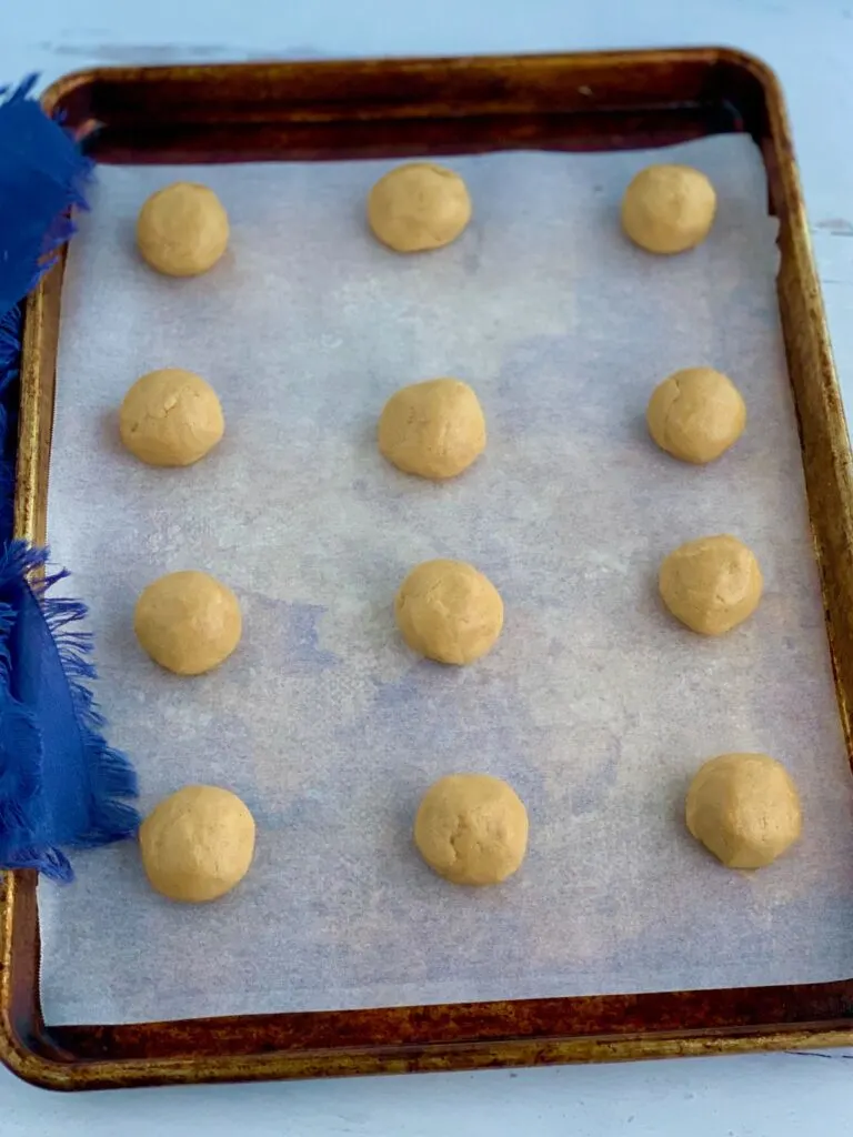 A baking sheet full of round peanut butter balls