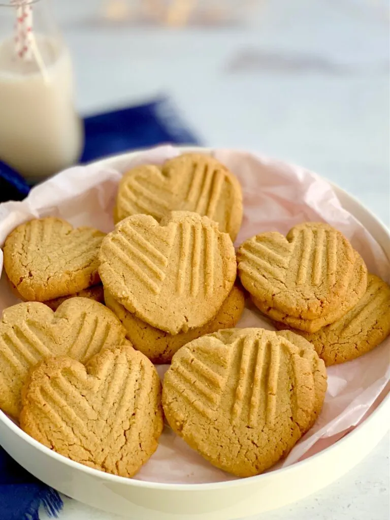 Heart-shaped peanut butter cookies with the classic criss cross pattern on them on a platter.