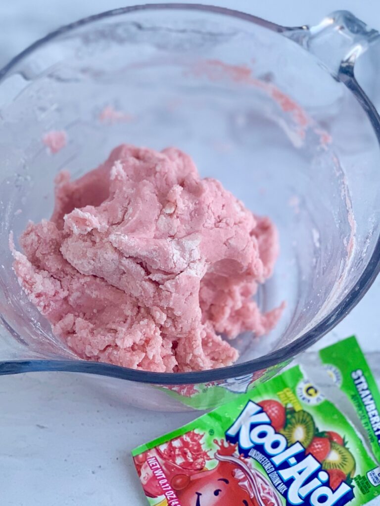 A ball of playdough started to come together as a ball in a glass mixing bowl. 