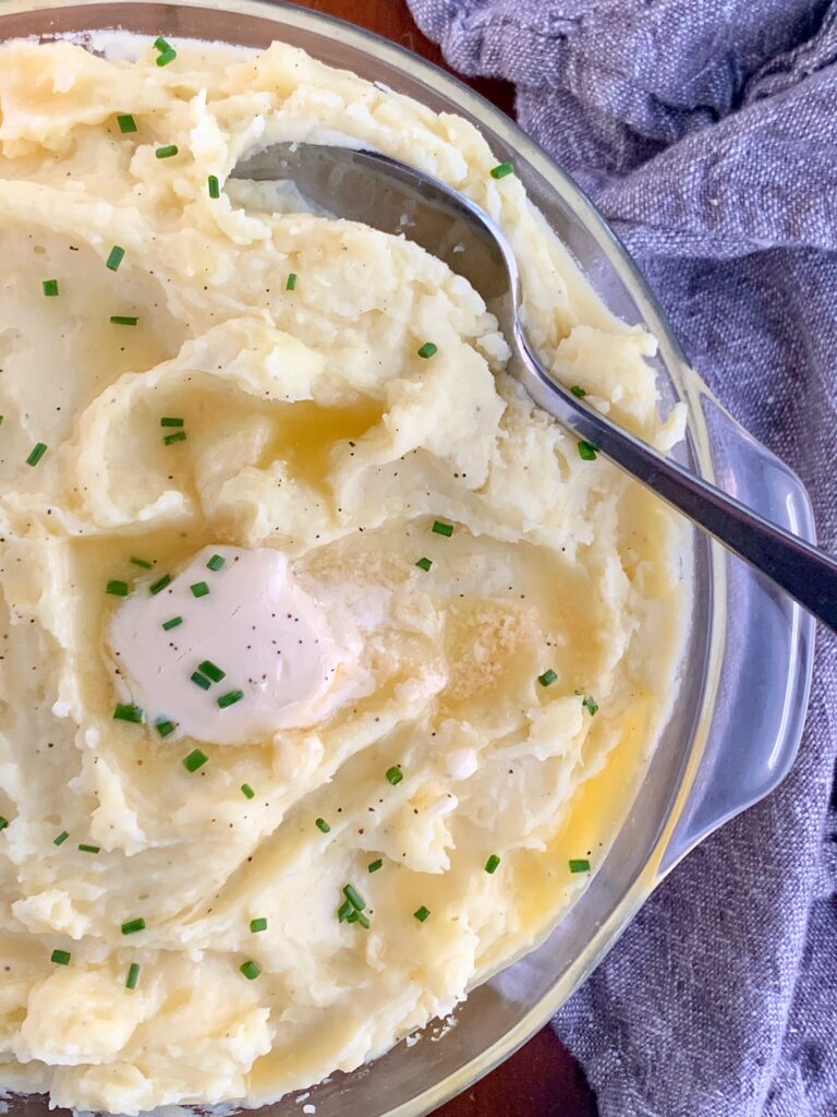 A big bowl of creamy mashed potatoes with melting butter on top.