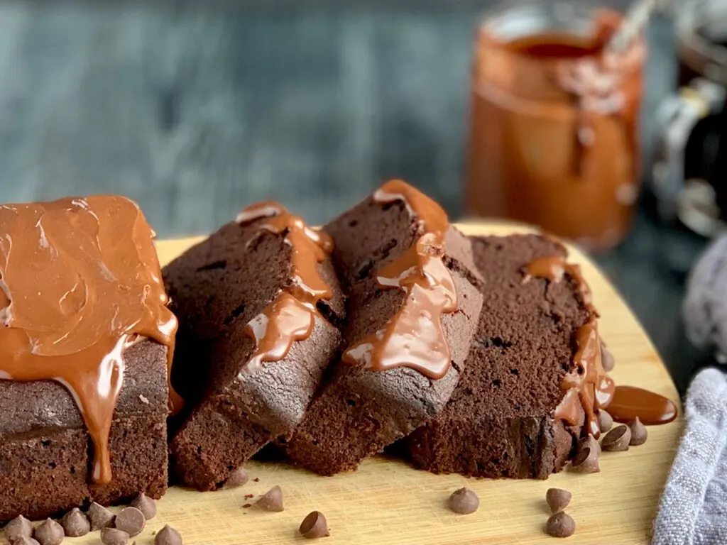 Sliced chocolate loaf cake with a runny ganache topping on it.