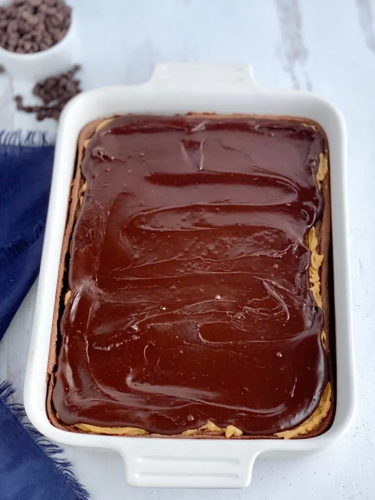 A baked chocolate brownie mix in a white 9X13-inch baking pan with crunchy peanut butter over the cooled brownie. Then the bars are topped with a chocolate marshmallow mixture.