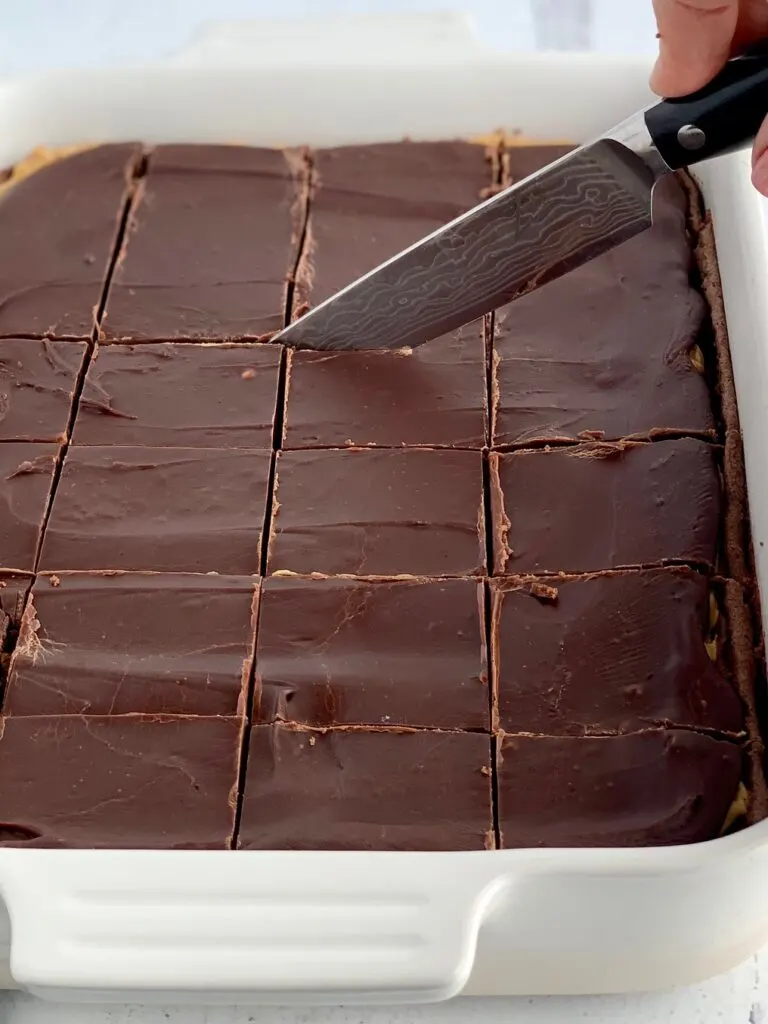 A knife cutting bars in a 9 x 13-inch baking pan.