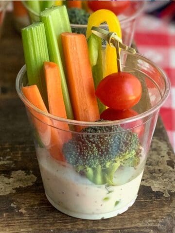 A cup with dairy free ranch and veggies.