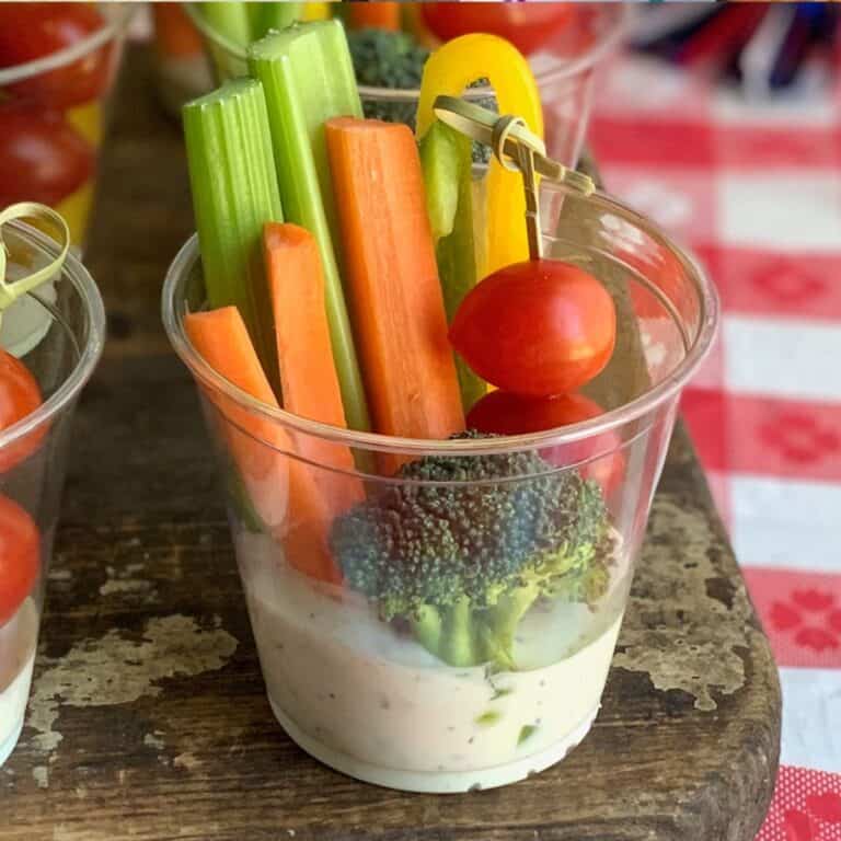 A cup with dairy free ranch and veggies.