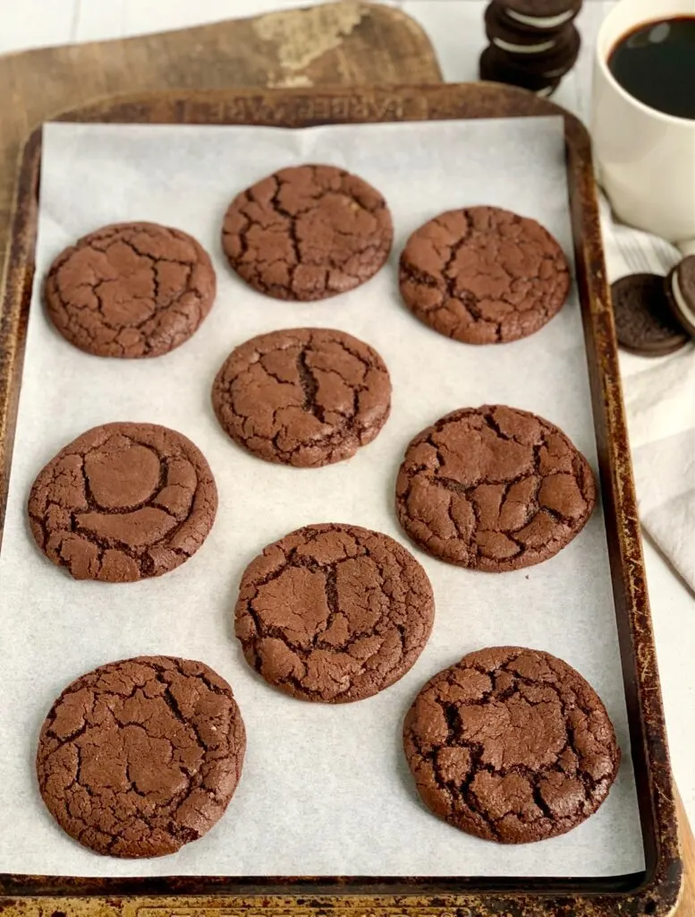 A large cookie sheet with 9 baked brownie cookies on it.