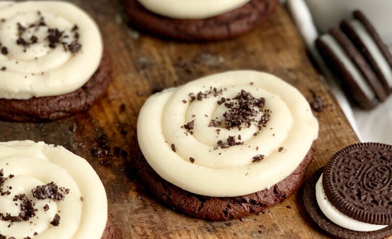 A round brownie cookie topped with vanilla buttercream frosting in a swirl and crushed oreo cookies on top.