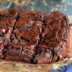 An 8x8-inch square baked brownie cut into 12 slices on a cutting board.