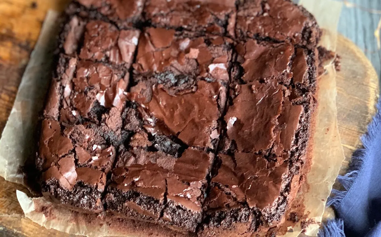An 8x8-inch square pan of baked brownies on a cutting board.