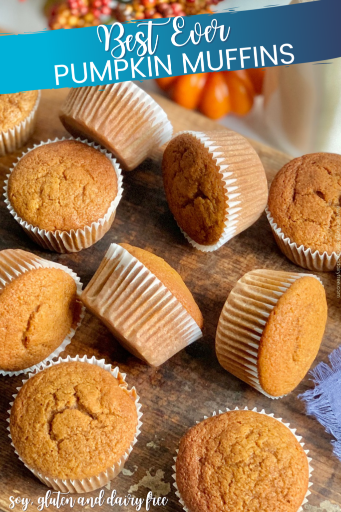 Pumpkin colored muffins in white muffins liners scattered across a dark serving platter.