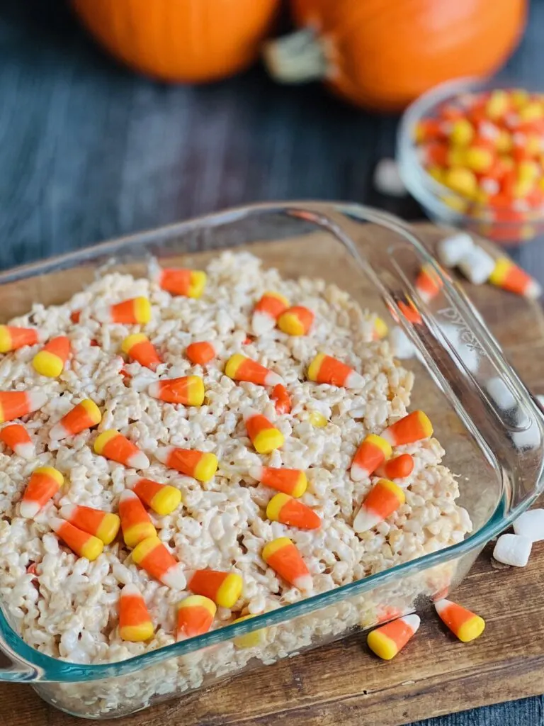 Rice krispie cereal coated in melted marshmallow with candy corns on top cut into squares.