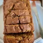 A large loaf of golden colored quick bread with large slices and chocolate chips in it.