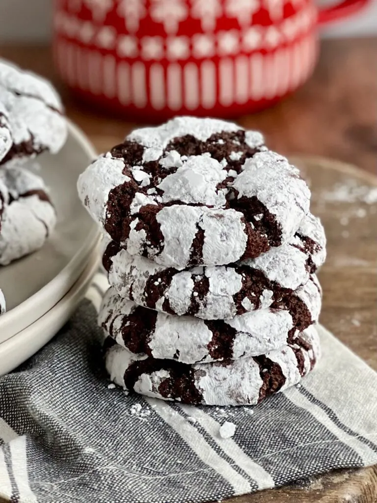 4 dark chocolate cookies with powdered sugar over them stacked on top of each other.