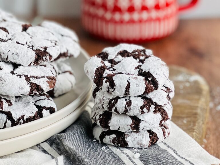 4 dark chocolate colored cookies with a powder sugar covering stacked on top of each other.