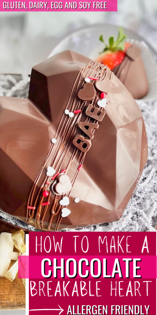 A chocolate heart sitting on a decorative plate with chocolate covered strawberries nearby. There is melted chocolate drizzled across the front with red and white sprinkles and the word BAE in chocolate.