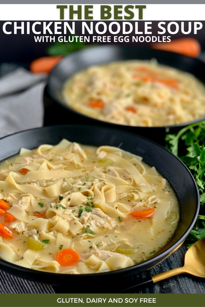 Two large black soup bowls filled with diced celery, carrots and wide noodles with chunks of chicken and broth. On top are a few fresh cut parsley pieces.