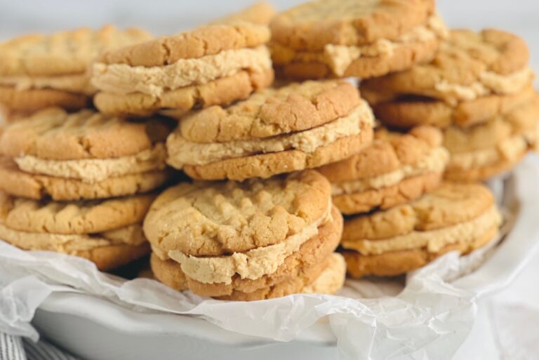 A plate full of peanut butter cookies with a brown thick frosting in the middle.