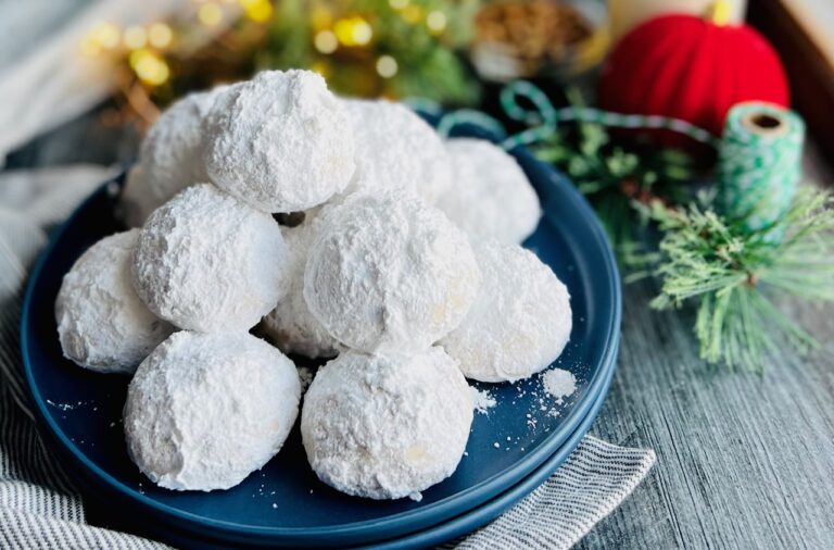A blue cookie plate full of white fluffy looking cookies piled on top of each other.