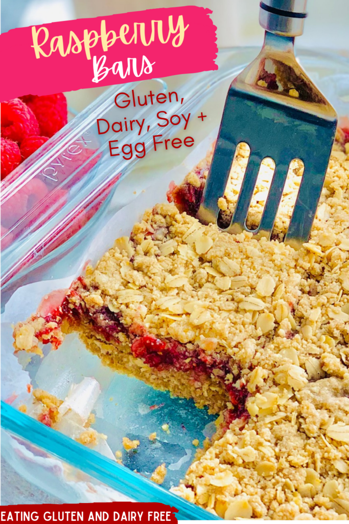 A glass 9x13-inch baking dish filled with a layer of oatmeal crumble, then a red raspberry layer and lastly it is topped with another layer of oatmeal crumble. The bars have been cut into slices and and bar is removed.