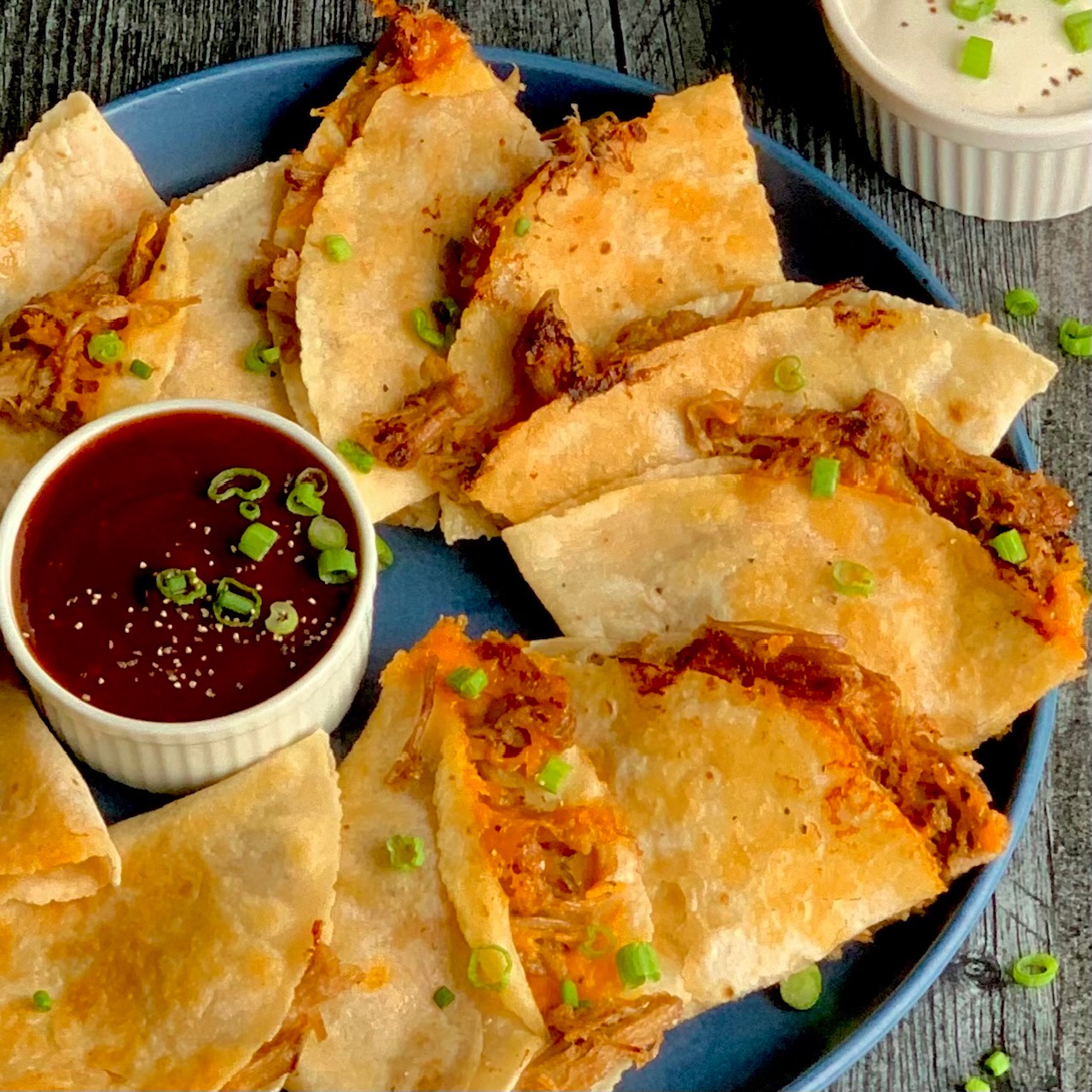 Pulled pork quesadillas with dip on a plate.