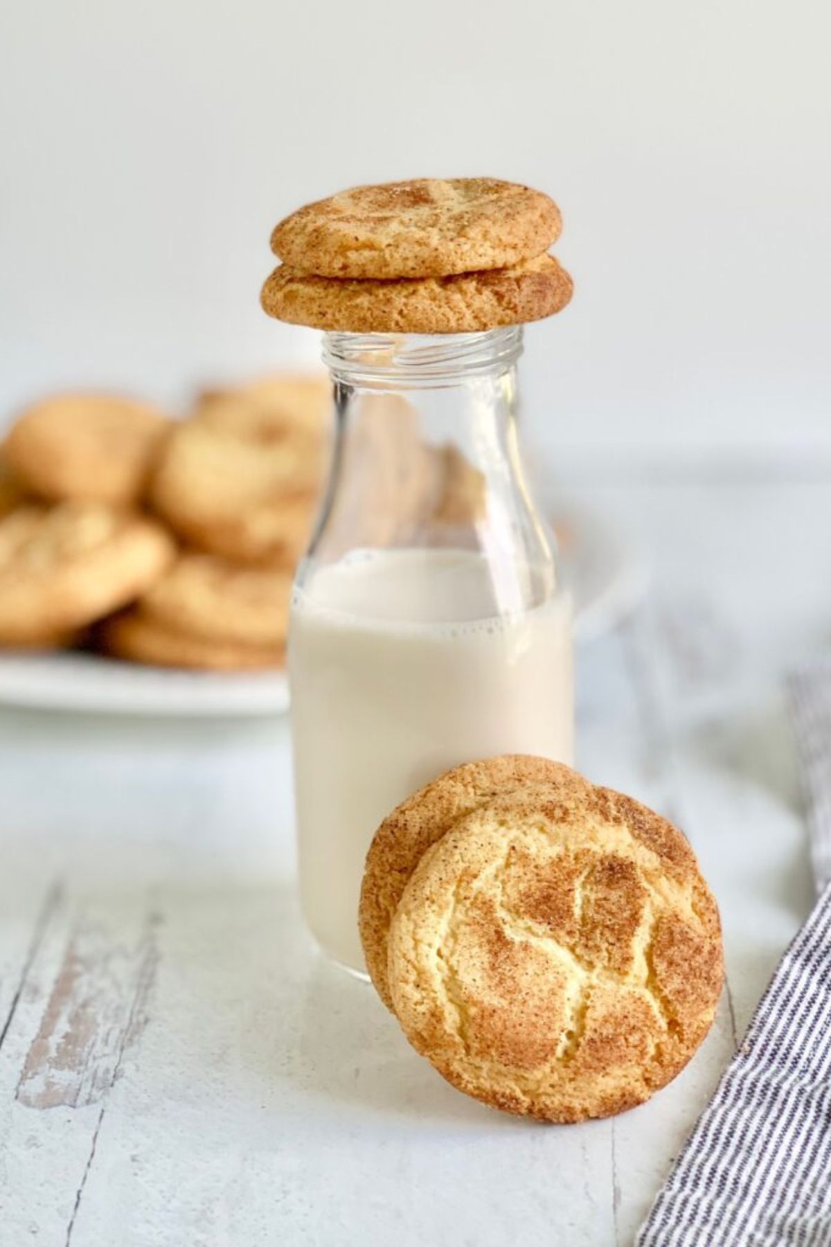 A glass jar of almond milk with a gluten free snickerdoodle on top and one in front of it.