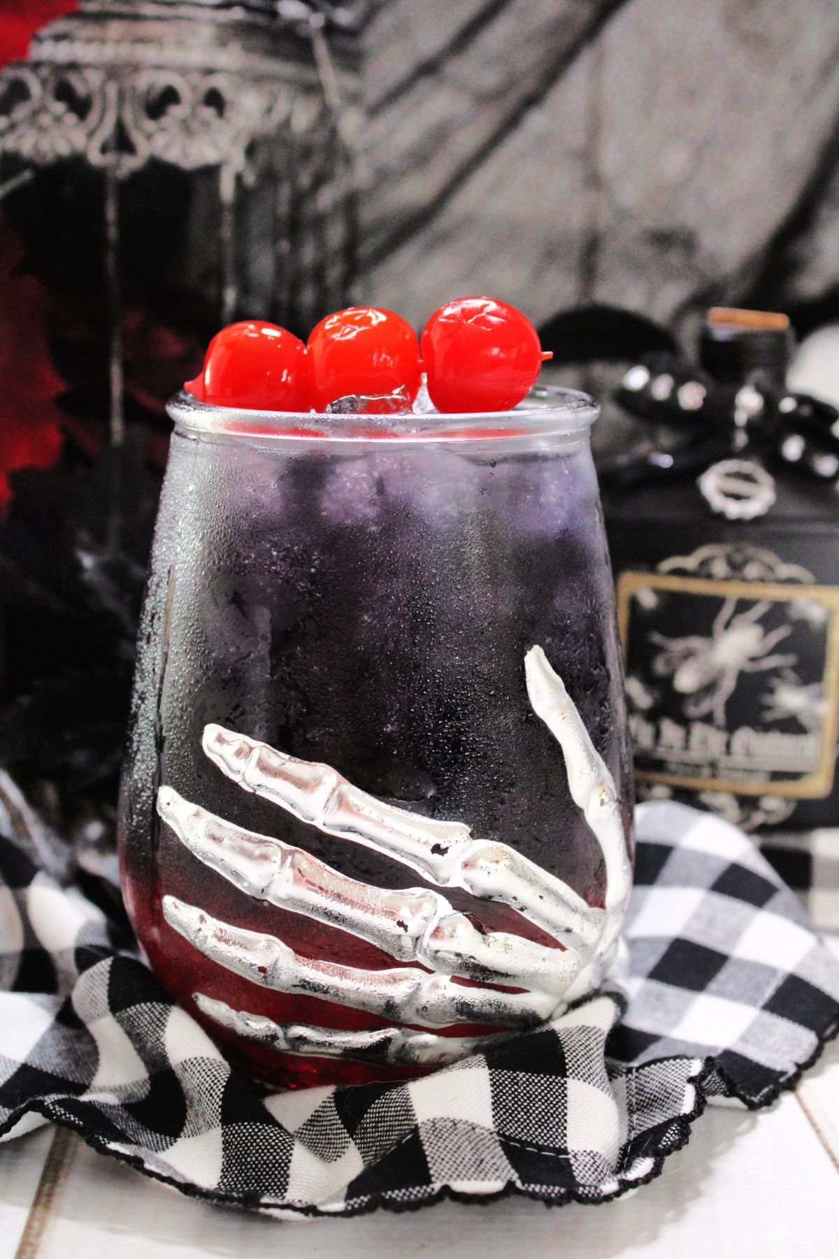 A Halloween glass with a Black Widow drink and cherries on top.